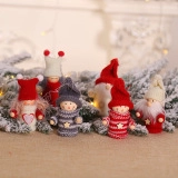Detail of wooden Christmas sleigh dolls with knit hats and stars on pine branches