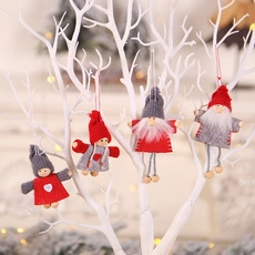 Close-up of red and grey knitted Christmas gnomes hanging on white branches