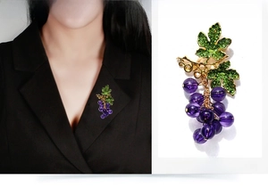Detailed macro view of a crystal grape brooch with purple beads and gold metal leaves