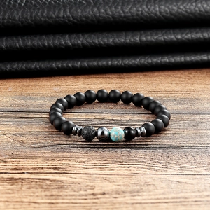 Close-up of matte black obsidian and turquoise yoga bead bracelet on wooden desk