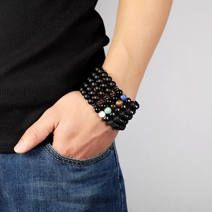 Close-up of five matte black beaded yoga bracelets with multi-colored stone accents