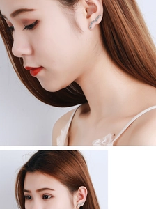 Detail showing curved wave-shaped silver earrings with sparkling crystals on a model