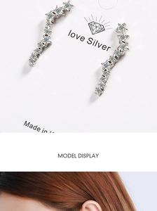 Detailed view of silver star drop earrings with sparkling rhinestones on model