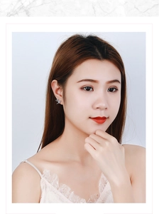 Close-up of sparkling heart-shaped silver earrings with cubic zirconia on female model