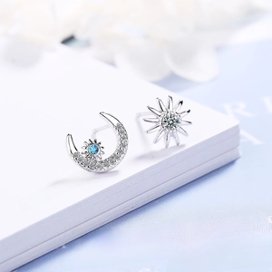 Asymmetric moon and sun stud earrings with blue and white zircon in silver finish