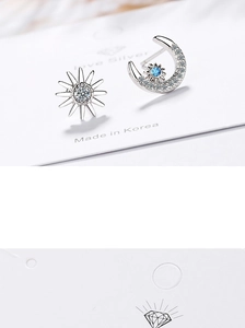 Detail of silver asymmetric celestial earrings with sun, moon and blue gemstone accents