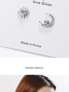 Close-up of asymmetric silver star and moon stud earrings with sparkling crystals