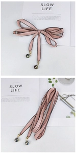 Écharpe étroite rose avec bords noirs et pendentifs en perles irisées sur magazine