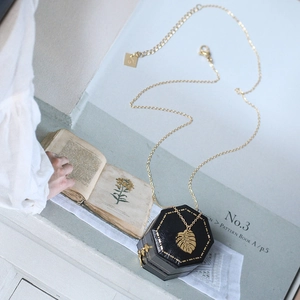 Tropical palm leaf pendant necklace in gold-plated steel on vintage botanical background