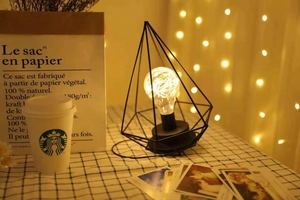 Detail of Nordic iron art lamp with glowing bulb on a checkered tablecloth setting