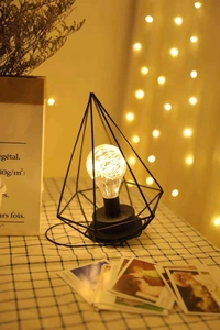 Nordic black iron pyramid table lamp with warm LED bulb and decorative background