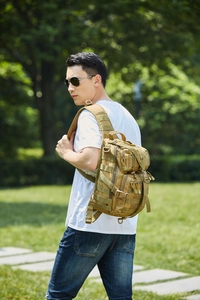 Tactical oxford saddle bag in khaki shown on a model in an outdoor park setting