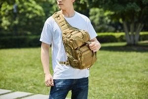 Tactical khaki chest bag with Molle system worn by a model in an outdoor park setting