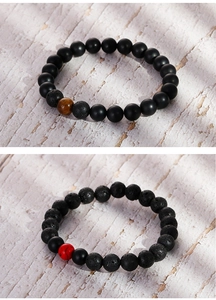Detailed macro view of 8mm matte black beads and lava stone bracelets on wood
