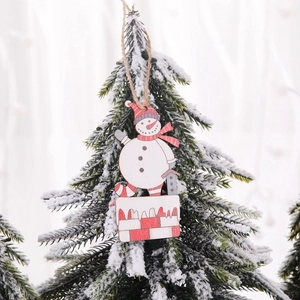 Hölzerner Weihnachts-Schneemann-Anhänger mit rotem Hut auf verschneiten Zweigen