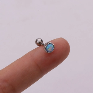 Close-up of small opal stud earring with silver gear bezel held on a fingertip