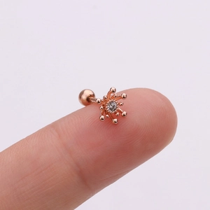 Détail d'une boucle d'oreille étoile en or rose avec une pierre en cristal