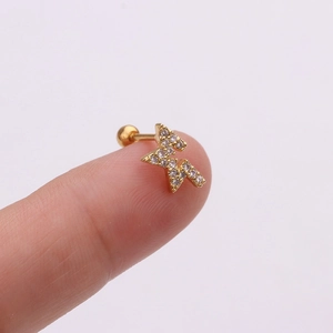 Macro d'une petite boucle d'oreille éclair en or avec cristaux sur le bout du doigt