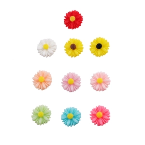 Flat lay macro view showing diverse colors of 12mm resin daisy flower charms for DIY