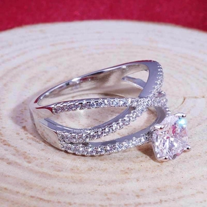 Anello in argento intrecciato con zircone rotondo su una base di legno naturale