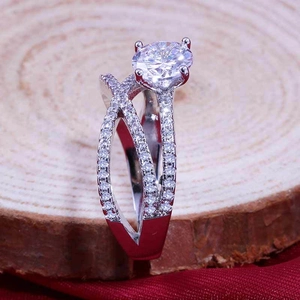 Close-up of a silver crossover engagement ring with a large brilliant round center stone