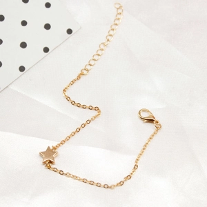 Detail of gold chain bracelet featuring lobster clasp and polished star charms