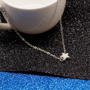 Macro shot of silver star pendant on fine chain draped over a ceramic cup edge