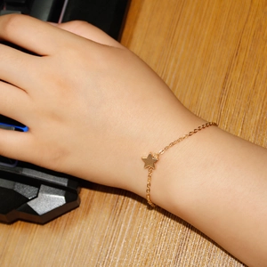Detail showing minimalist gold star charm bracelet on wrist with thin chain texture