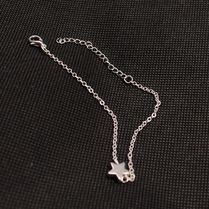 Detail of silver star charm bracelet with lobster clasp and adjustable chain on black fabric