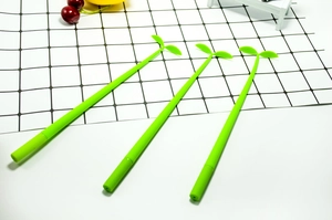 Close-up of three creative green sprout shaped silicone pens on a grid desk pad