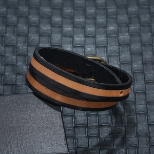 Dettaglio del bracciale multistrato in pelle intrecciata marrone e nera con chiusura in metallo