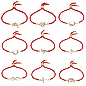 Detail von roten geflochtenen Kordelarmbändern mit goldenen Anhängern und Zirkon