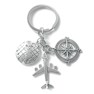 Silver travel keychain featuring earth globe, airplane and compass charms on white background