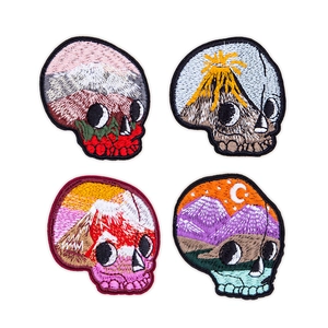 Close-up of skull shaped patches featuring embroidered nature scenery and vibrant mountain art