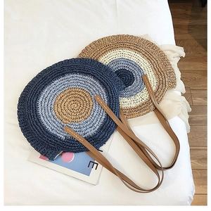 Détail d'un sac de plage rond en paille avec texture tressée et bandoulière en cuir brun