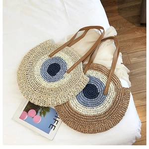 Détail de sacs ronds en paille tissée avec sangles en cuir et motifs circulaires bleus