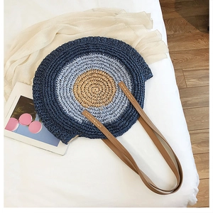 Détail du sac de plage rond en paille avec tissage dégradé bleu et anses en cuir