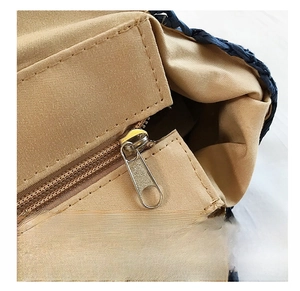 Détail de la fermeture éclair en métal sur le sac de plage en paille tressée pour femmes