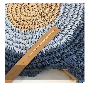 Détail macro du sac de plage rond en paille avec texture bleue et bandoulière en cuir