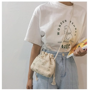 Detail view of beige woven bucket bag featuring green floral embroidery and drawstring