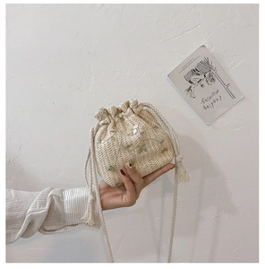 Detail of hand-woven bucket bag featuring green floral embroidery and drawstring closure