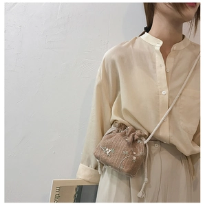 Close-up of a light brown woven bucket bag featuring delicate white flower embroidery