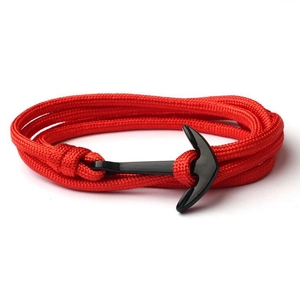 Detail of a red braided rope bracelet with a black anchor clasp on a white background
