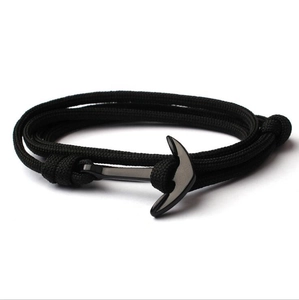 Macro detail of black braided nylon bracelet featuring a polished anchor clasp