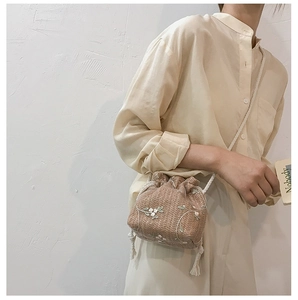 Detail of hand-woven straw bucket bag with delicate floral embroidery and rope drawstring