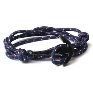 Macro detail of navy braided rope bracelet with black anchor clasp on white background