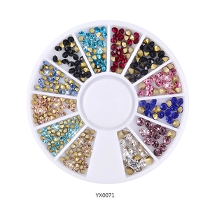 Detailed macro view of 12-color assorted nail art rhinestones in a white round wheel tray