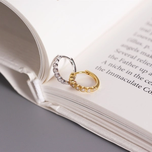 Detailed view of silver and gold S925 sterling silver huggie earrings with cubic zirconia