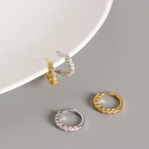 Macro detail of S925 sterling silver hoop earrings with zircon stones in gold and silver