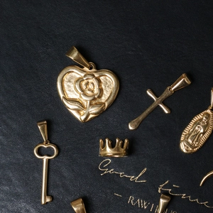 Macro shot of five assorted gold-plated pendants on a black leather surface